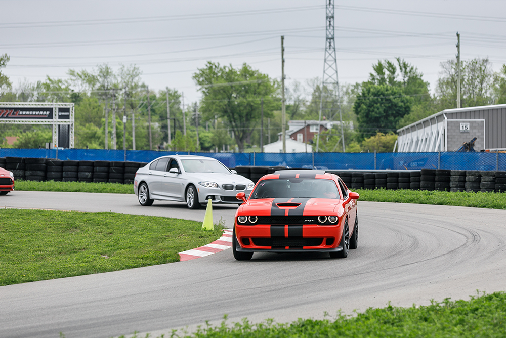 Red Dodge sports car rounding a track corner with cars close behind